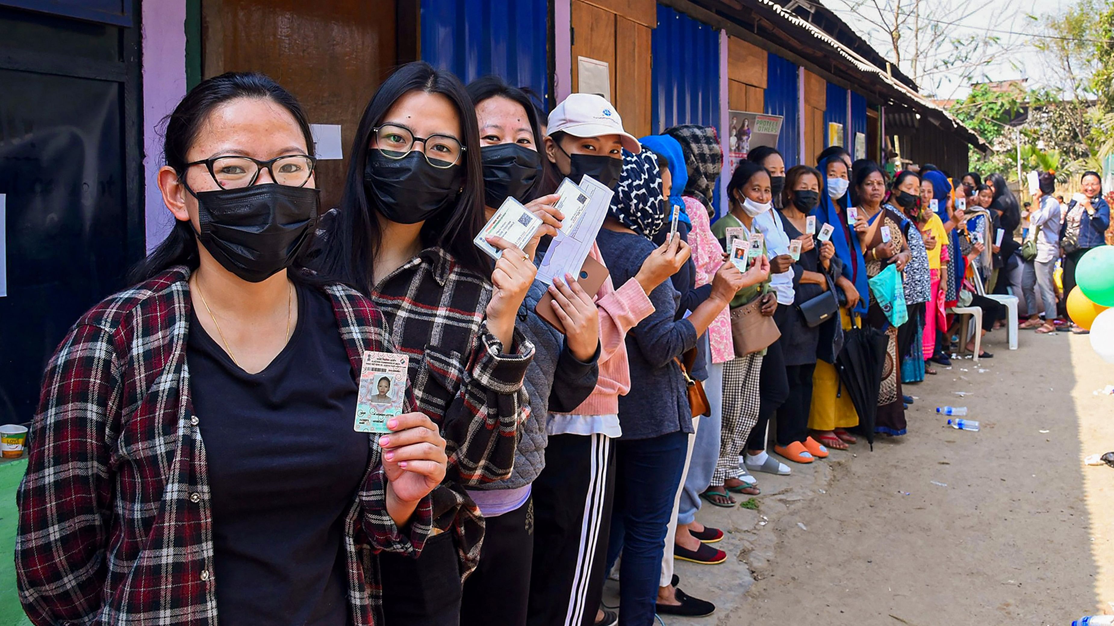 <div class="paragraphs"><p>Voters standing in a queue show their ID cards before casting their votes.&nbsp;</p></div>