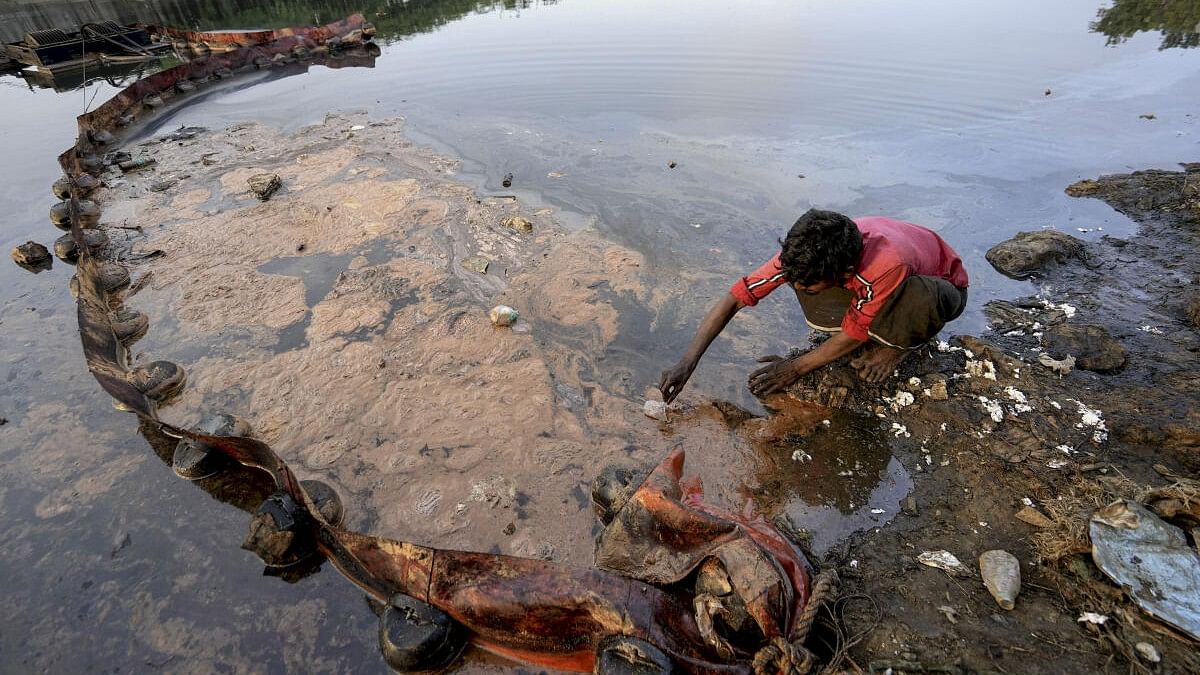 <div class="paragraphs"><p>A man sits near an oil Trap placed at the Ennore Creek area after a recent oil spill in the Bay of Bengal off in the aftermath of Cyclone Michaung, in Chennai, Friday, Dec. 22, 2023.</p></div>