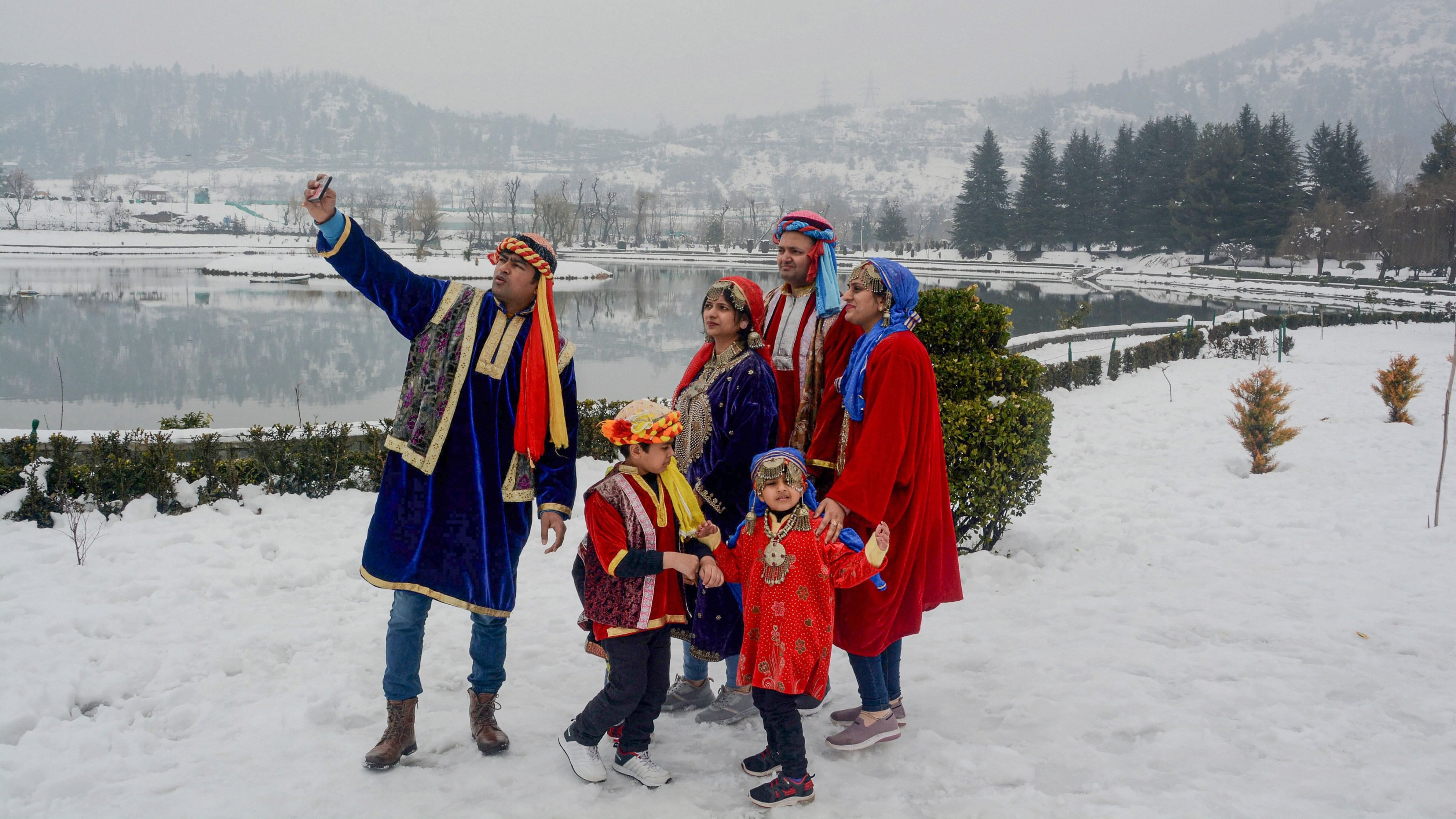 <div class="paragraphs"><p>Tourists wearing traditional Kashmiri dresses click a selfie, during their visit to the botanical gardens after winter snowfall, in Srinagar.&nbsp;</p></div>