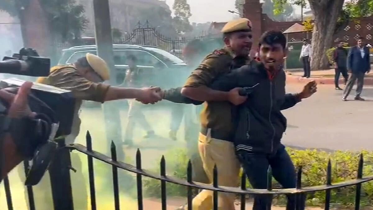 <div class="paragraphs"><p>Police personnel apprehend a man carrying a can emitting yellowish smoke while he was protesting outside the Parliament premises, during the Winter session, in New Delhi, Wednesday, Dec. 13, 2023.</p></div>