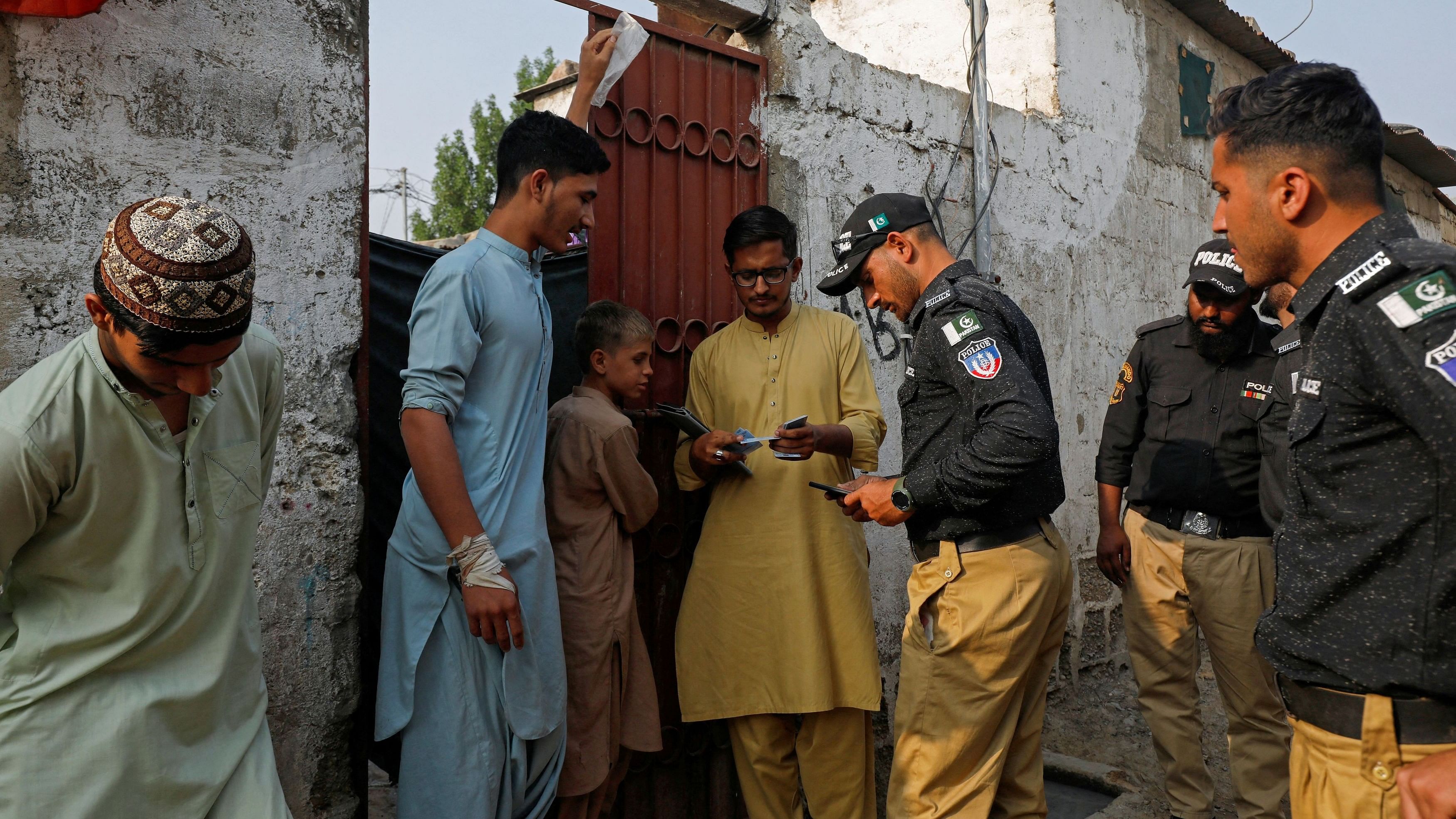 <div class="paragraphs"><p>Police officers and NADRA workers check the identity cards of Afghan citizens during a door-to-door search and verification drive for undocumented Afghan nationals, in an Afghan Camp on the outskirts of Karachi, Pakistan, November 21, 2023.</p></div>