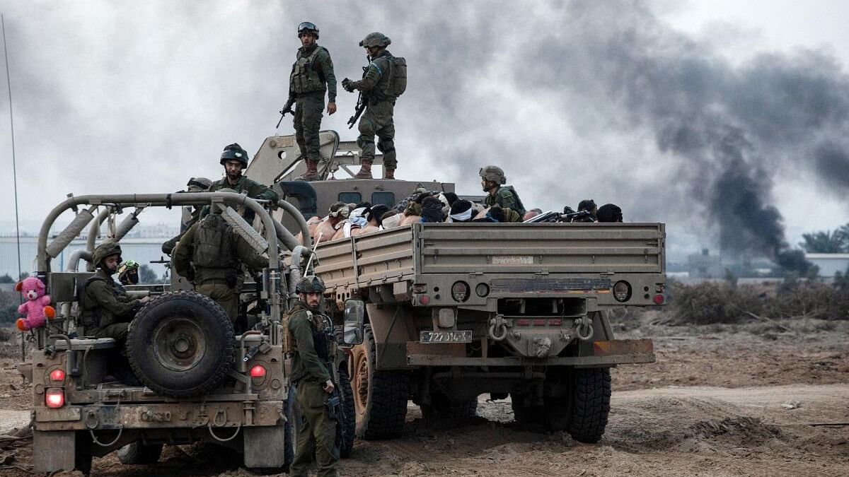 <div class="paragraphs"><p>Palestinian detainees sit in a truck as Israeli soldiers guard around amid the ongoing conflict between Israel and the Palestinian Islamist group Hamas, in the Gaza Strip December 8, 2023.</p></div>