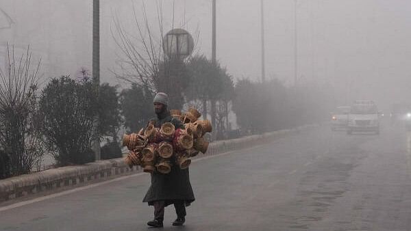 <div class="paragraphs"><p>A vendor selling 'kangris', the traditional Kashmiri firepots, crosses a road amid dense fog, in Srinagar.</p></div>