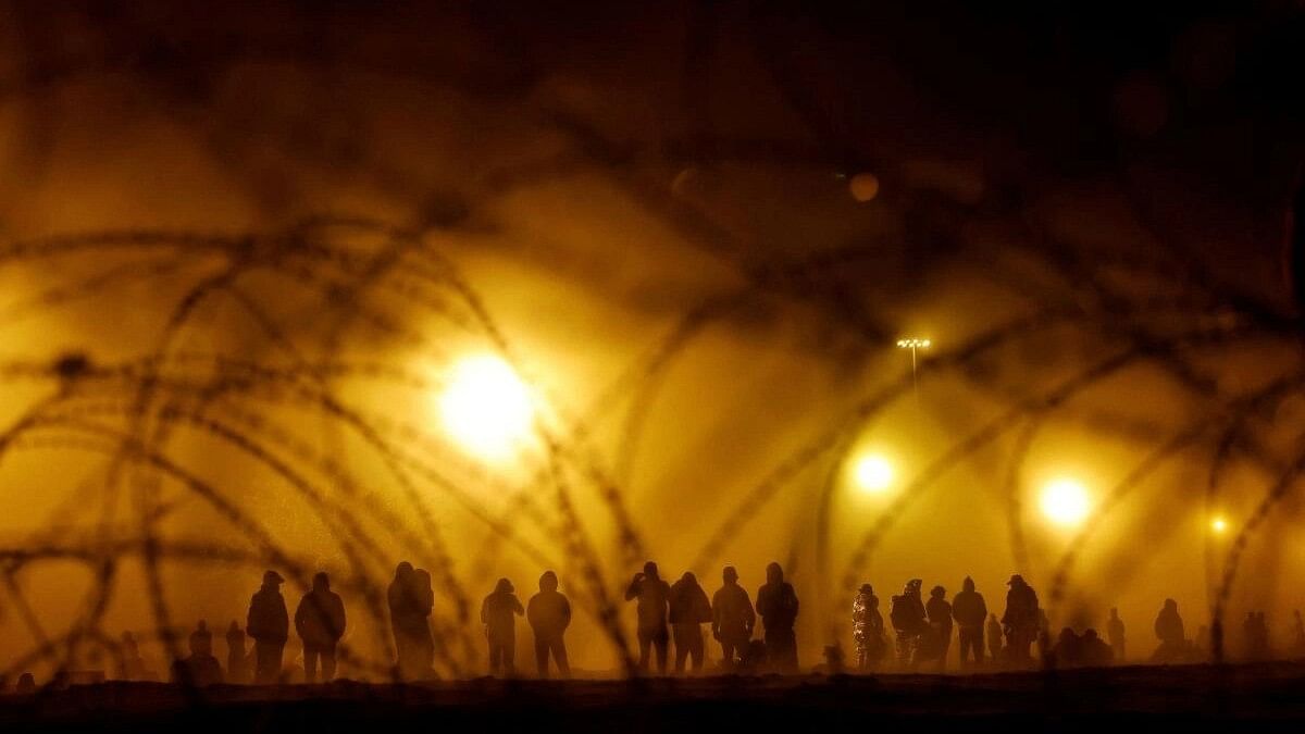 <div class="paragraphs"><p>Migrants stand near the US-Mexico border wall during a sandstorm.</p></div>