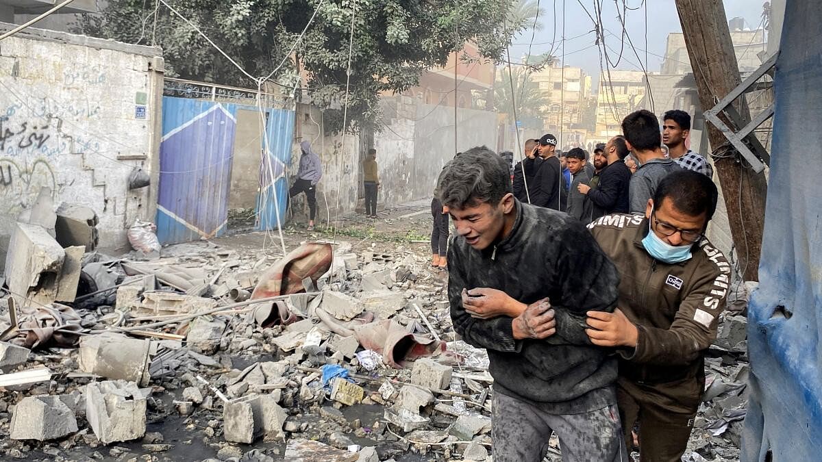 <div class="paragraphs"><p>A Palestinian assists a boy following an Israeli strike on a house, after a temporary truce between Hamas and Israel expired, in Rafah, in the southern Gaza Strip December 1, 2023.</p></div>