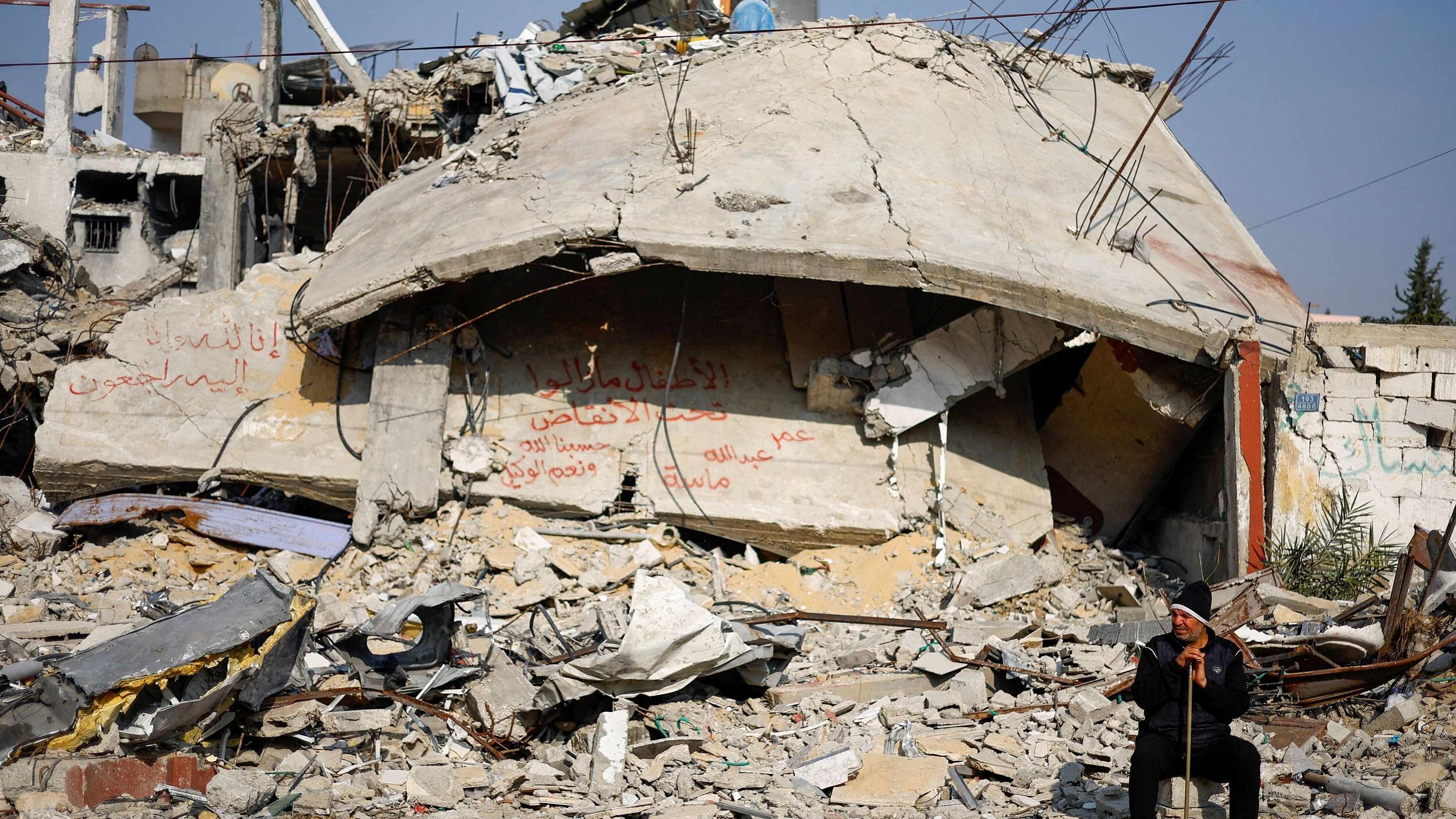 <div class="paragraphs"><p>Ziad Mansour, a neighbour of the Abu Aweidah family, sits next to writing painted on a wall amid the rubble of the family's house, which was destroyed in a deadly Israeli strike amid the ongoing conflict between Israel and the Palestinian Islamist group Hamas.</p></div>