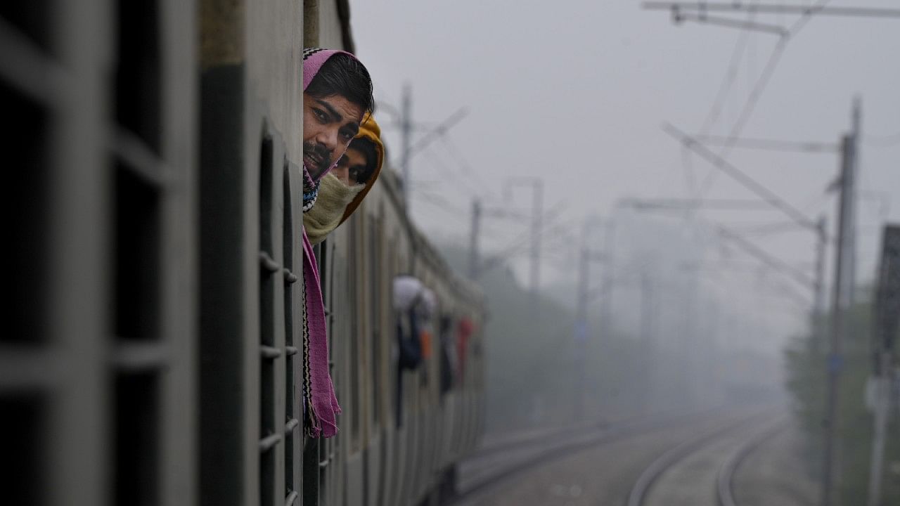 <div class="paragraphs"><p>Passengers look on as they stand at the gates of an EMU train which got delayed during a cold and foggy winter morning, in New Delhi. </p></div>