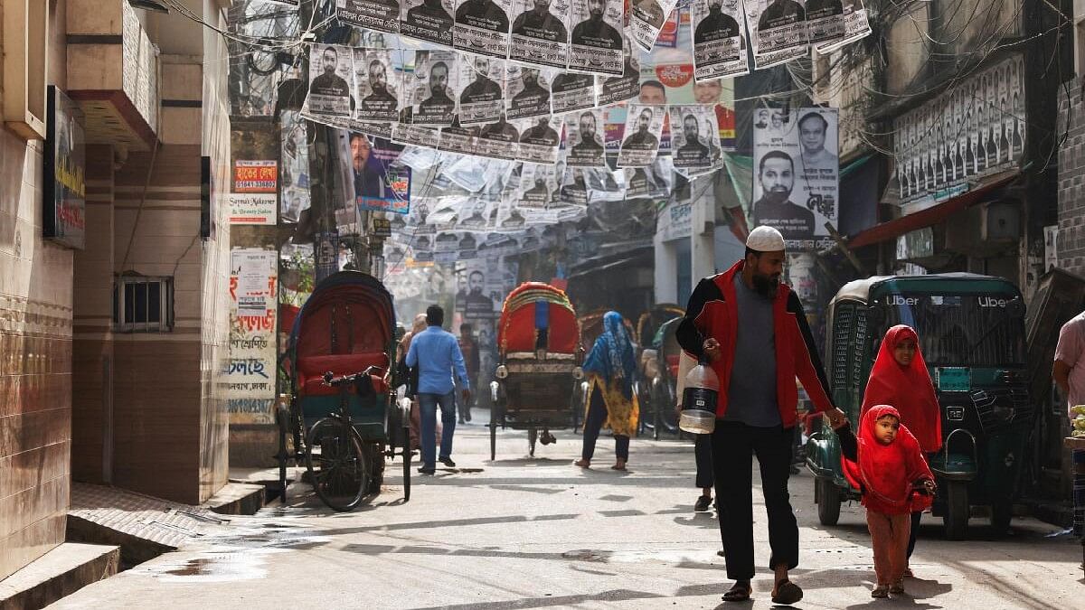 <div class="paragraphs"><p>Commuters pass by as posters of an election candidate hang on the street ahead of the general election in Dhaka.</p></div>