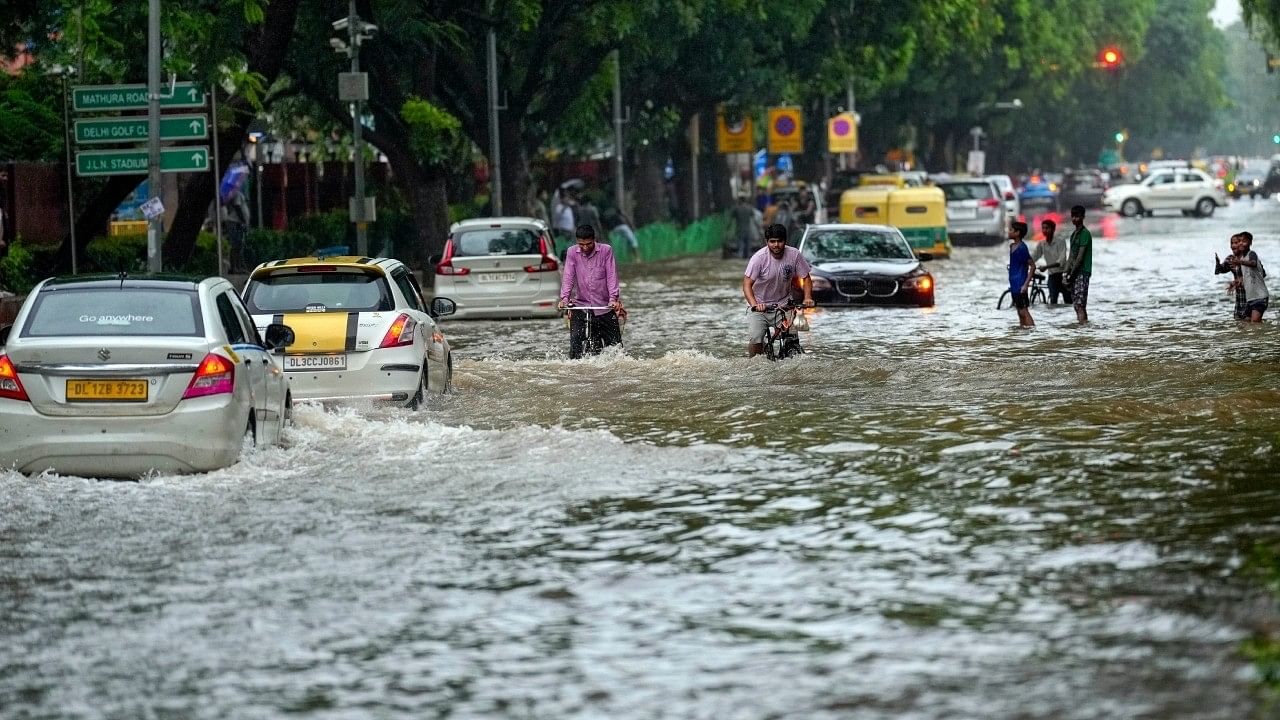 <div class="paragraphs"><p>Commuters move through a waterlogged road at Rabindra Nagar in New Delhi. </p></div>