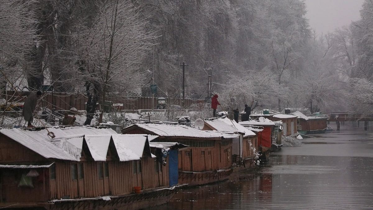 <div class="paragraphs"><p>People remove snow from the roofs of their houseboat during a snowfall in Srinagar.&nbsp;</p></div>
