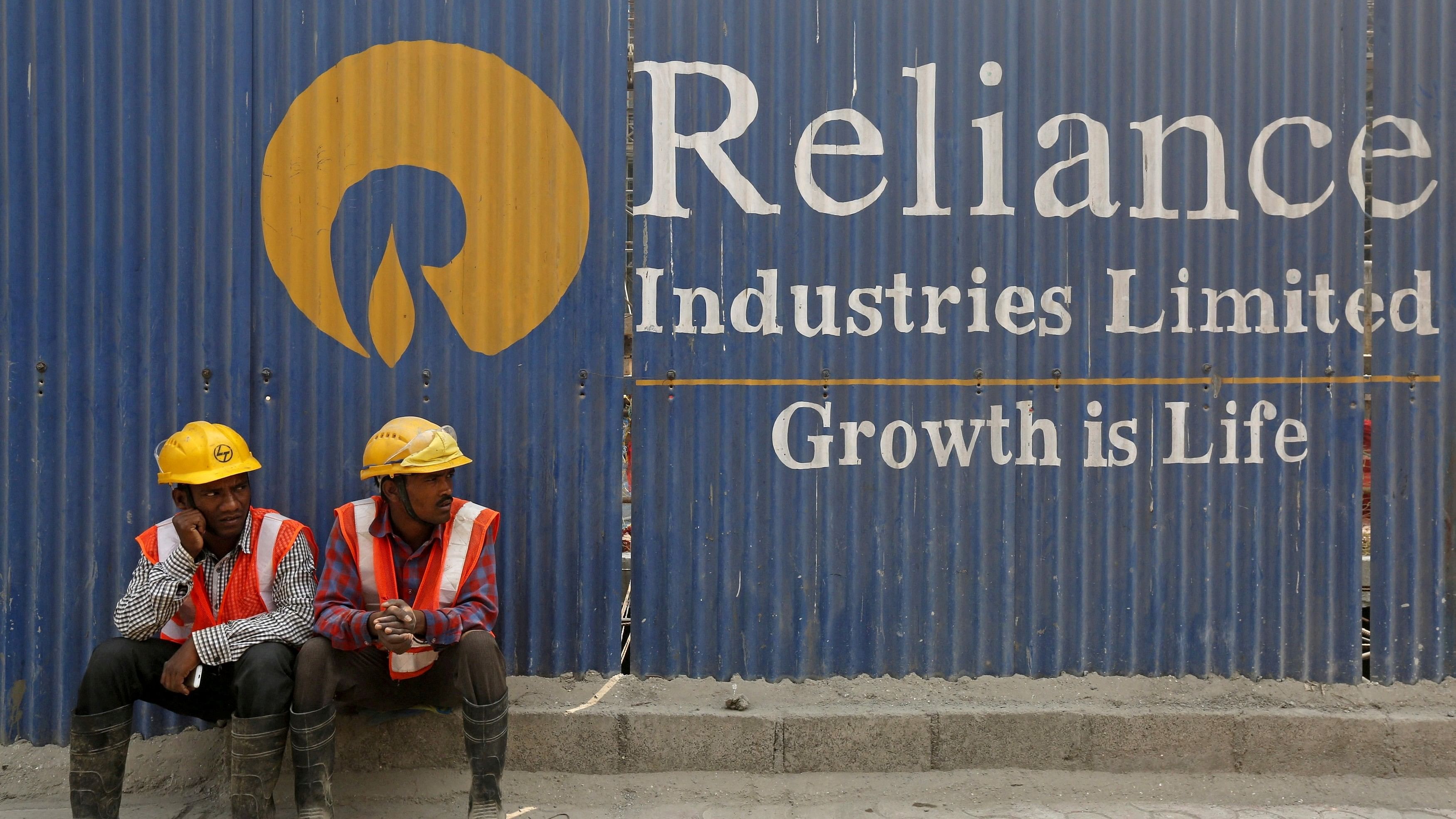 <div class="paragraphs"><p>Labourers rest in front of an advertisement of Reliance Industries Limited at a construction site in Mumbai.</p></div>