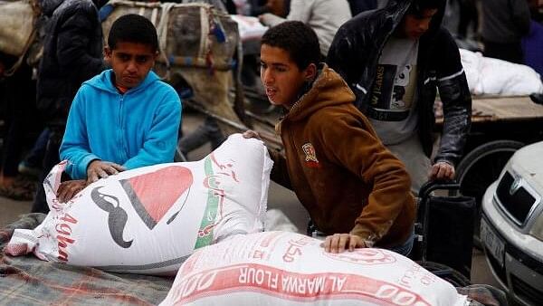 <div class="paragraphs"><p>Palestinians gather to receive bags of flour distributed by UNRWA, in Rafah.</p></div>