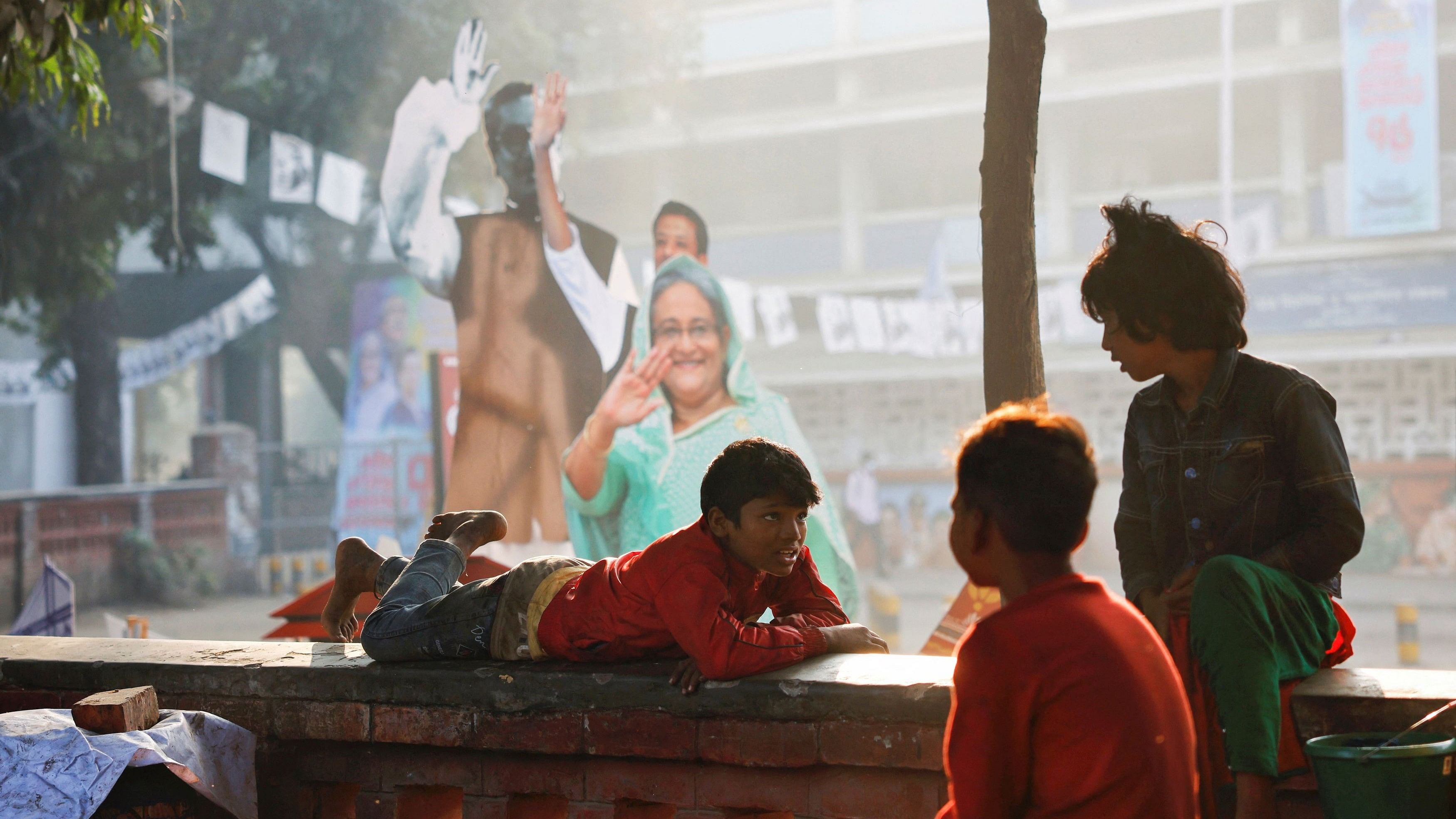 <div class="paragraphs"><p>Children chat at the University of Dhaka with an installation of the picture of Sheikh Hasina, Prime Minister and Chairman of Bangladesh Awami League in the background, a day ahead of the general election in Dhaka, Bangladesh, January 6, 2024. </p></div>