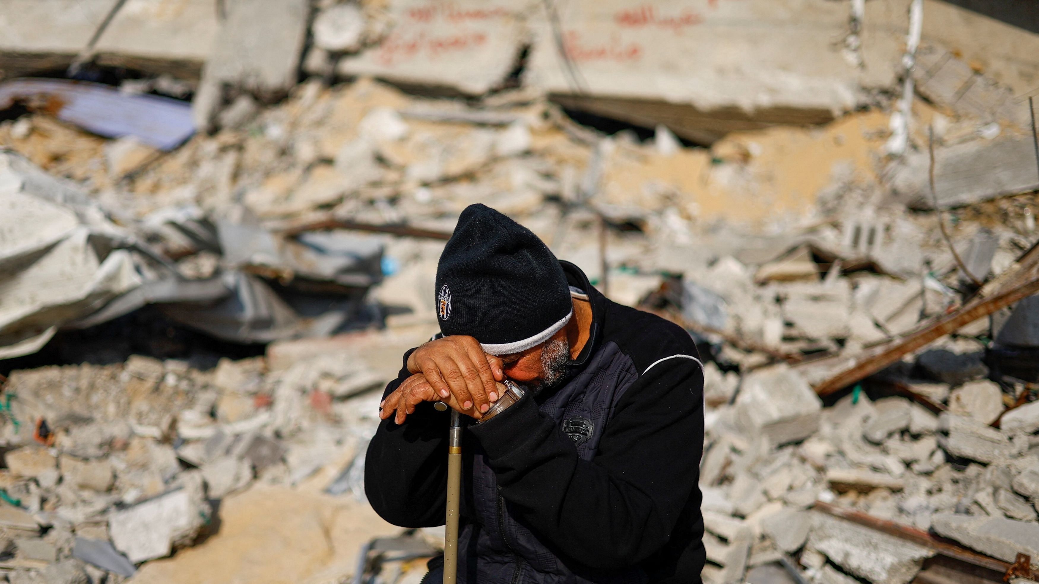 <div class="paragraphs"><p>Ziad Mansour, a neighbour of the Abu Aweidah family, sits next to writing painted on a wall amid the rubble of the family's house, which was destroyed in a deadly Israeli strike amid the ongoing conflict between Israel and the Palestinian Islamist group Hamas, in Rafah, Gaza Strip, January 9, 2024. </p></div>