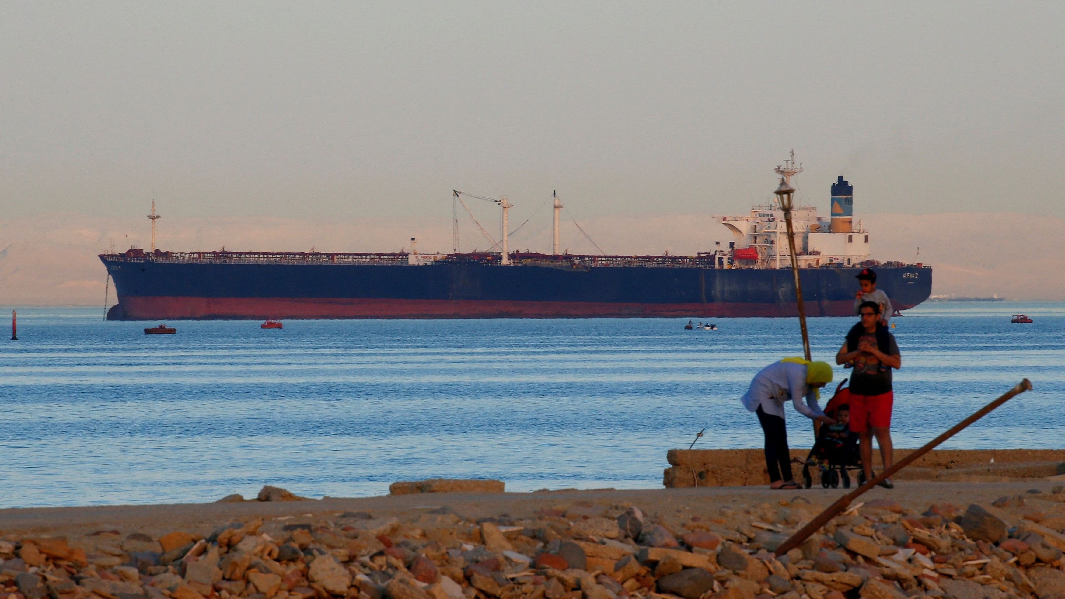 <div class="paragraphs"><p> People walk on the beach as a container ship crosses the Gulf of Suez towards the Red Sea.</p></div>