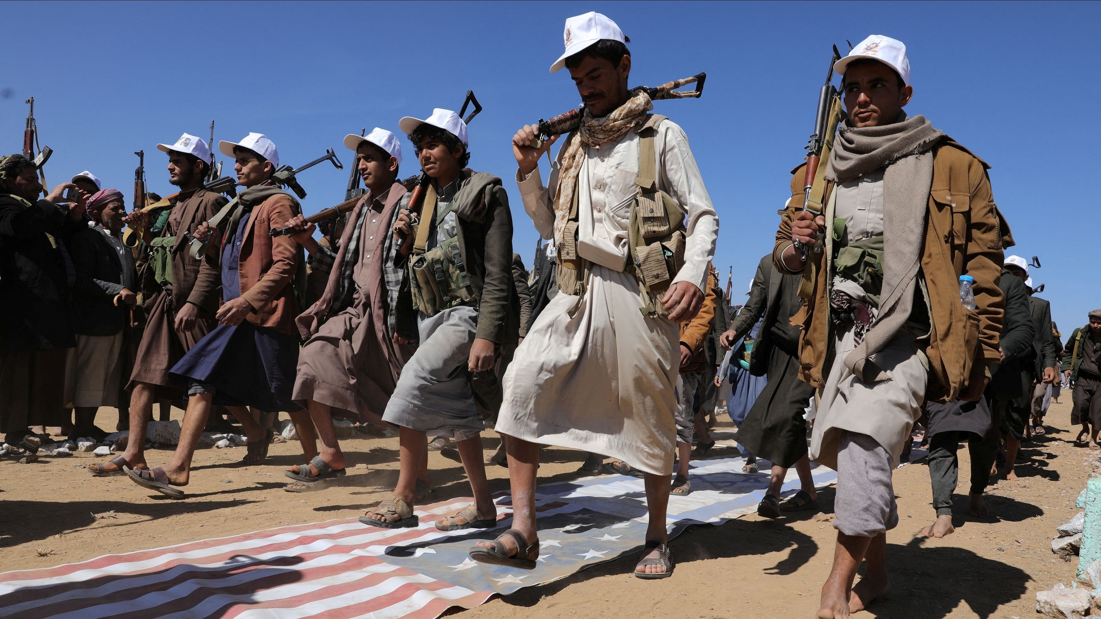 <div class="paragraphs"><p>Tribesmen loyal to the Houthis march on U.S. and Israeli flags during a military parade for new tribal recruits amid escalating tensions with the US-led coalition in the Red Sea, in Bani Hushaish, Yemen.</p></div>