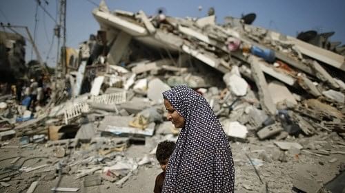 <div class="paragraphs"><p>A Palestinian woman walks past the rubble of a residential building, which police said was destroyed in an Israeli air strike, in Gaza City.</p></div>