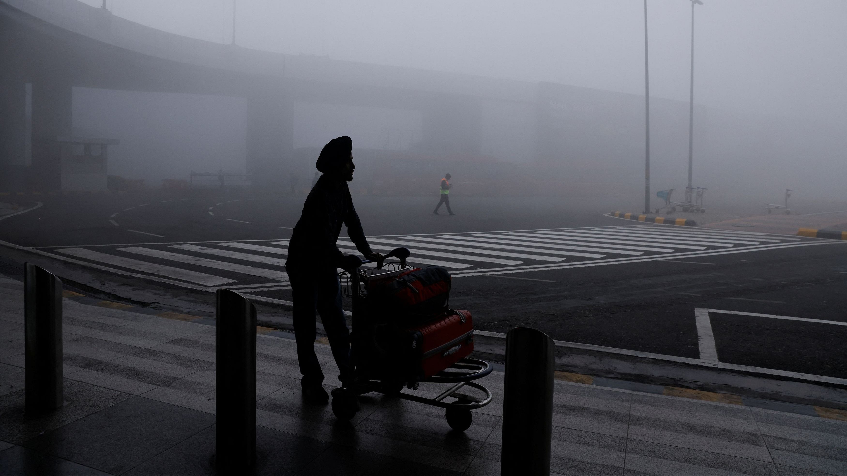 <div class="paragraphs"><p>A man is seen with his luggage cart amidst heavy fog at the Indira Gandhi International Airport in New Delhi.&nbsp;</p><p></p></div>