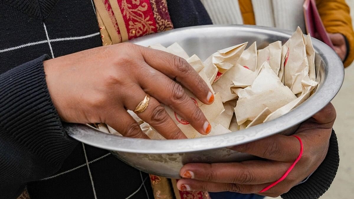 <div class="paragraphs"><p>A member of Shri Ram Janambhoomi Trust during distribution of ‘akshat’, rice grains mixed with turmeric and ghee, at Valmiki colony on the first day of the new year 2024, in Ayodhya.</p></div>