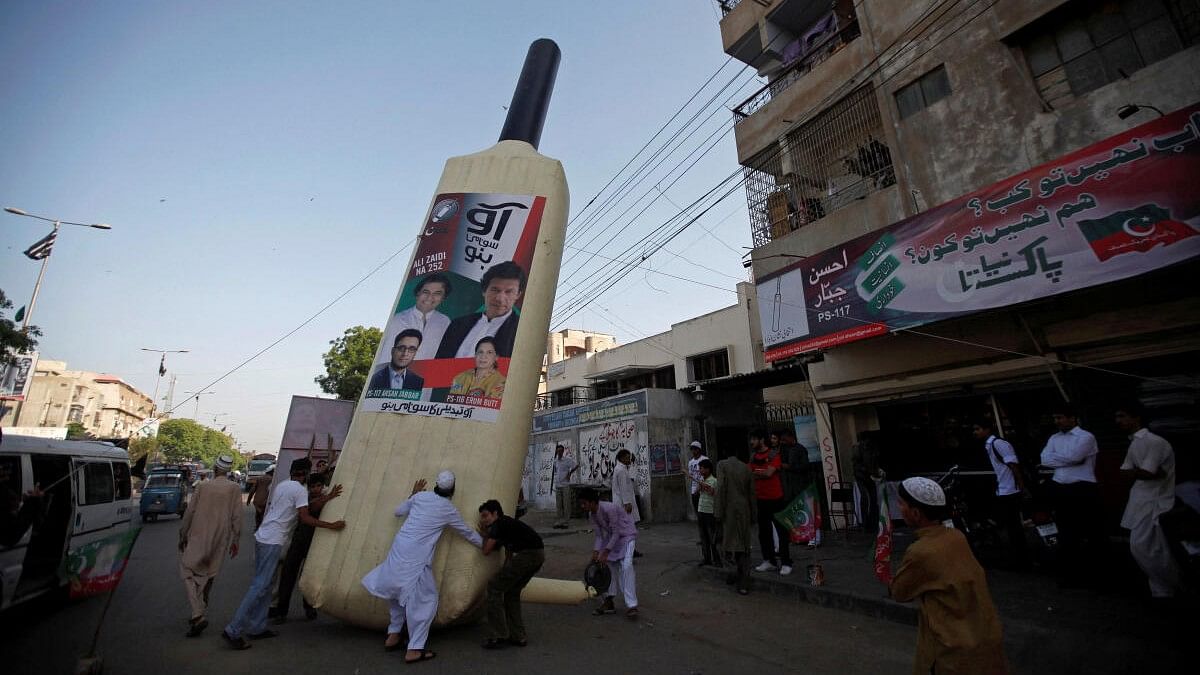 <div class="paragraphs"><p>Supporters of Imran Khan, Pakistani cricketer-turned-politician and chairman of political party PTI, install a giant bat symbol along a roadside in Karachi.</p></div>