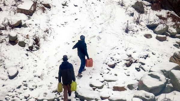 <div class="paragraphs"><p>People carry water cans over a snow covered hill after snowfall, at Tangmarg in Baramulla district of north Kashmir.</p></div>