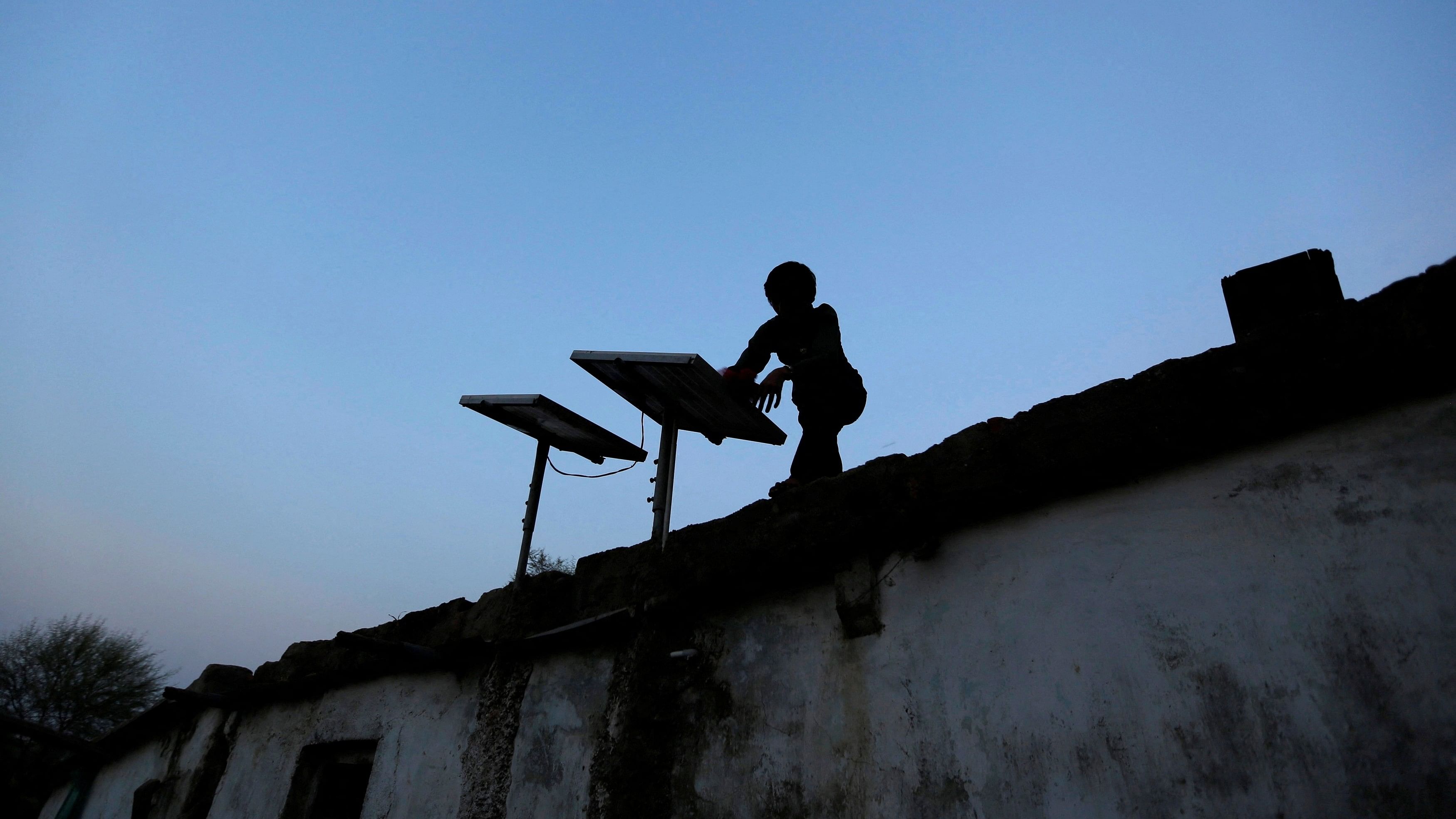 <div class="paragraphs"><p>A boy dusts off a solar panel installed on the rooftop of his house. Representative image.</p></div>