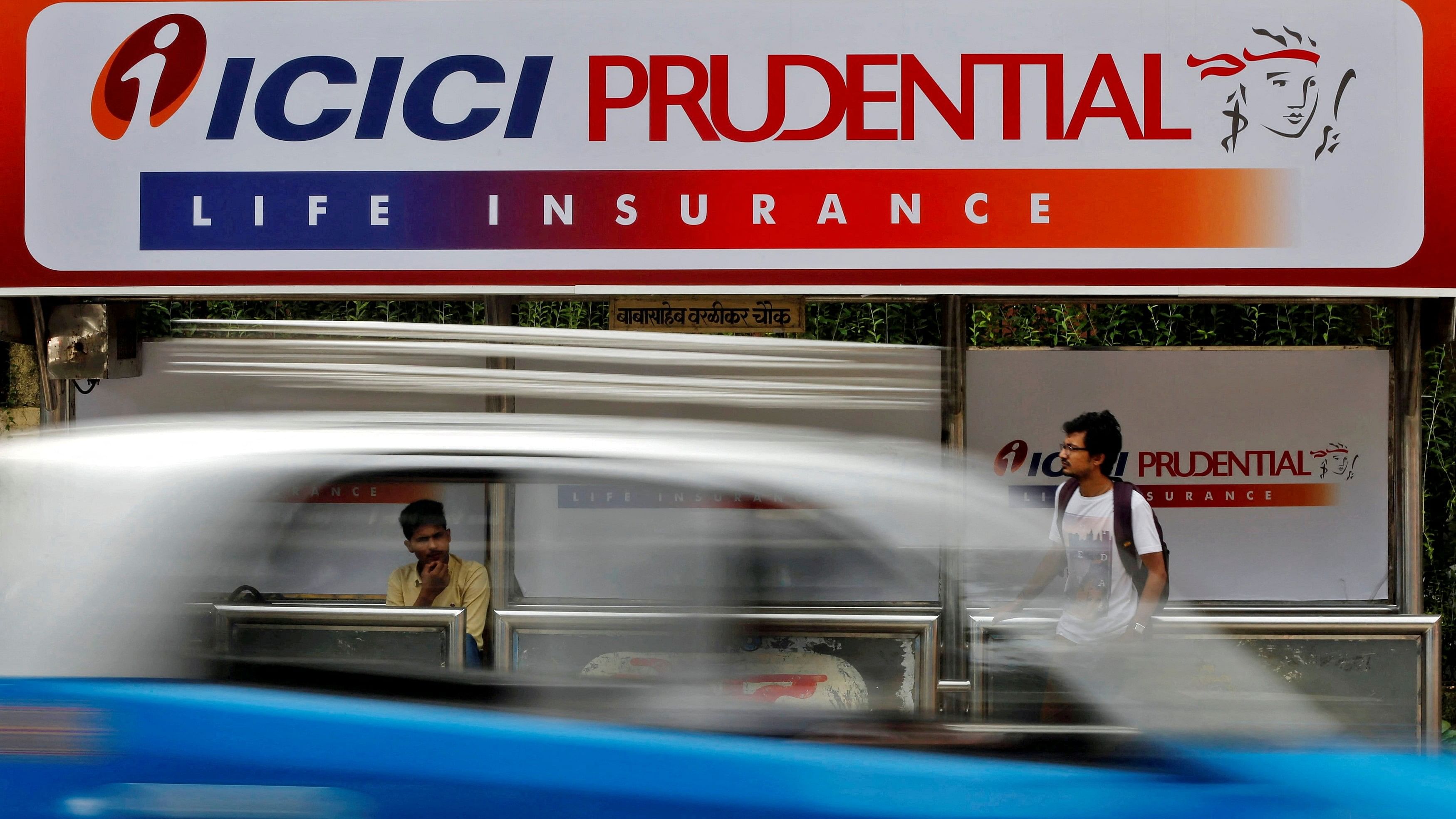 <div class="paragraphs"><p>Passengers wait in front of an ICICI Prudential billboard at a bus stop in Mumbai.</p></div>