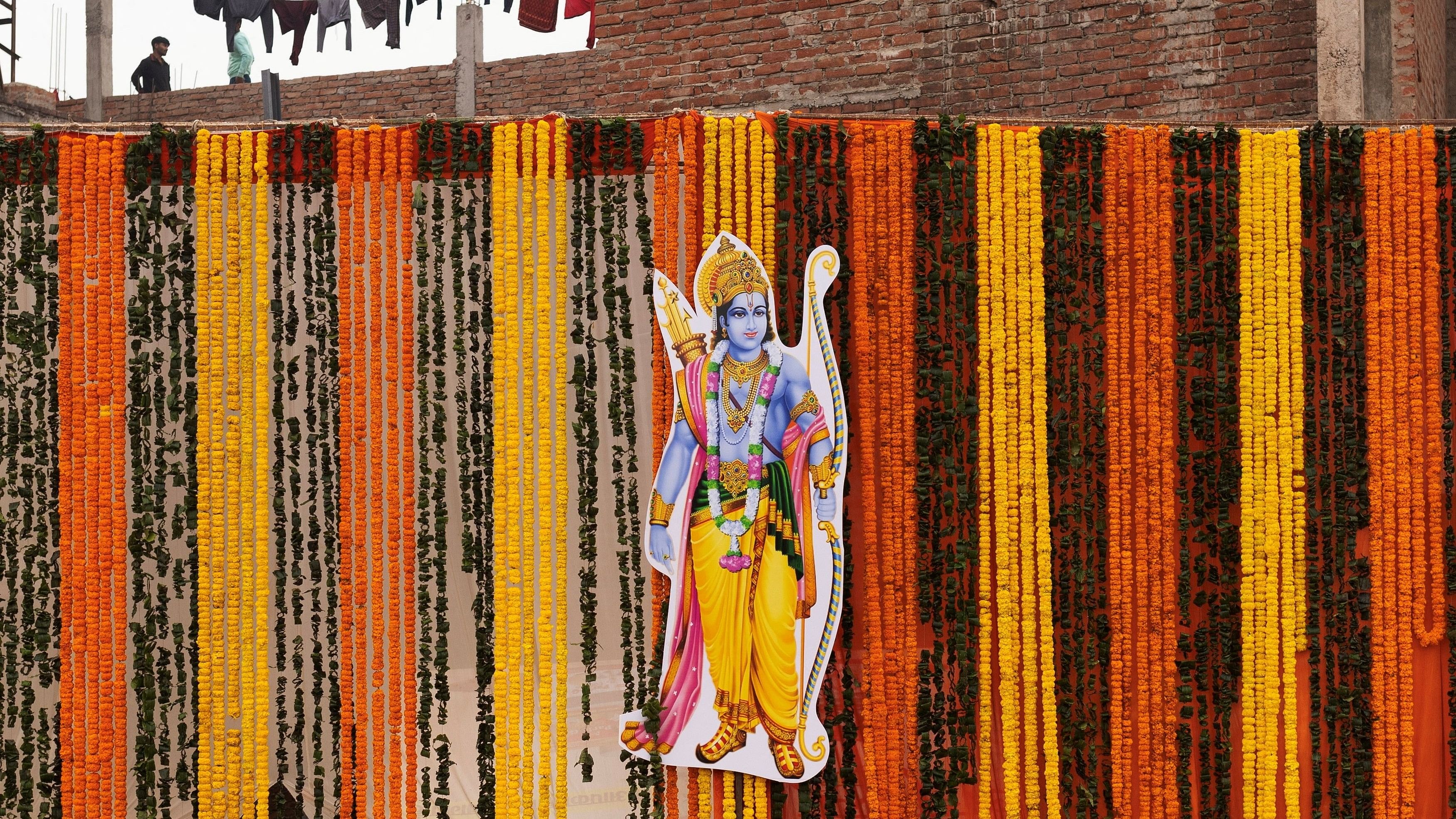 <div class="paragraphs"><p>Local residents stand on a rooftop as a cut-out of Hindu Lord Ram is attached to a wall decorated with flowers ahead of the opening of the temple of Lord Ram in Ayodhya.</p></div>