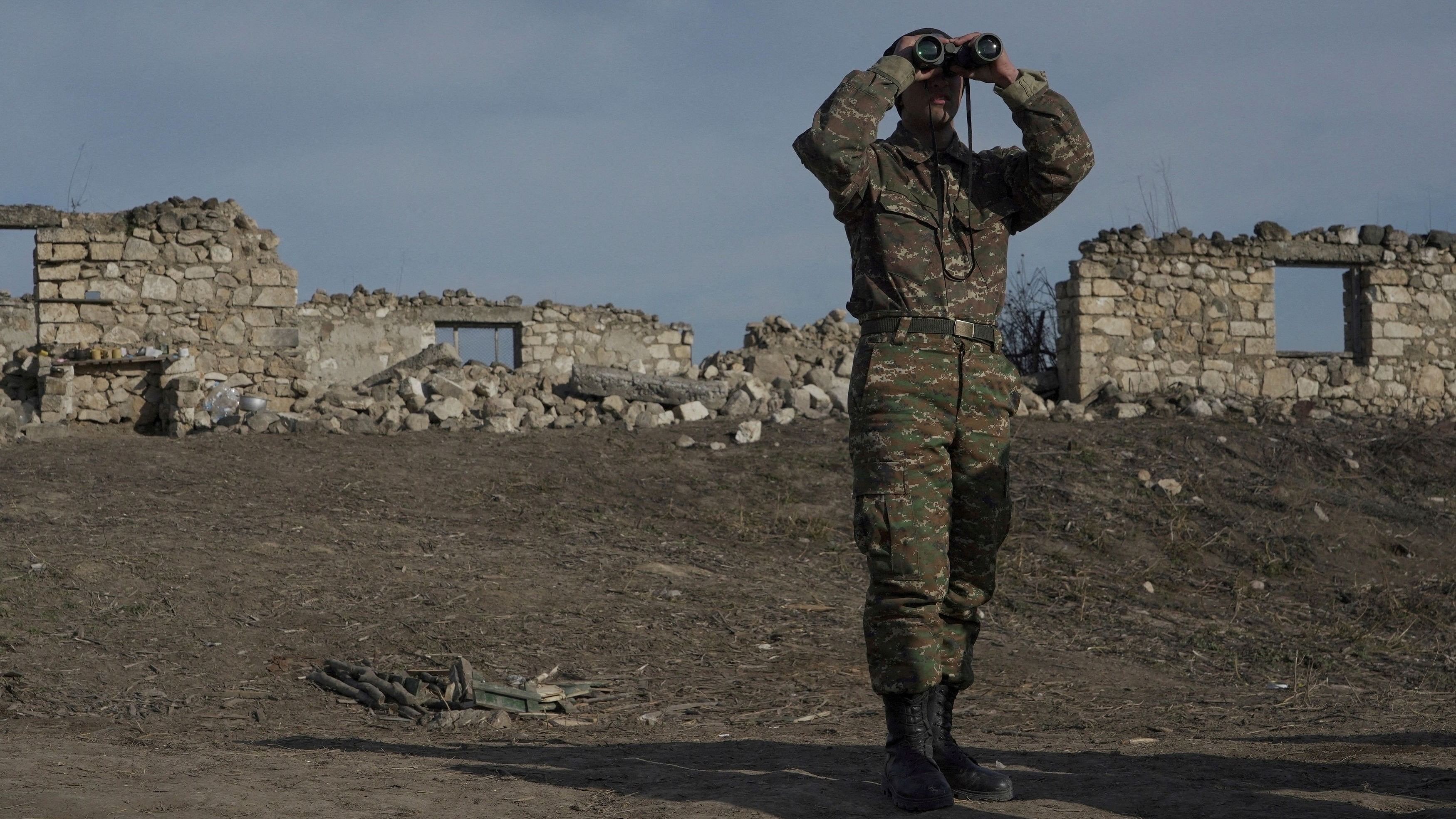 <div class="paragraphs"><p>A file photo of an Armenian soldier looks through binoculars as he stands at fighting positions near the village of Taghavard in the region of Nagorno-Karabakh.</p></div>