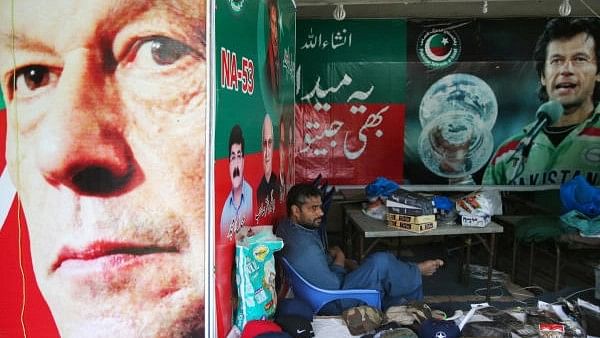 <div class="paragraphs"><p>A vendor sits next to images of cricket star-turned-politician Imran Khan, chairman of Pakistan Tehreek-e-Insaf (PTI) at a market in Islamabad, Pakistan.</p></div>