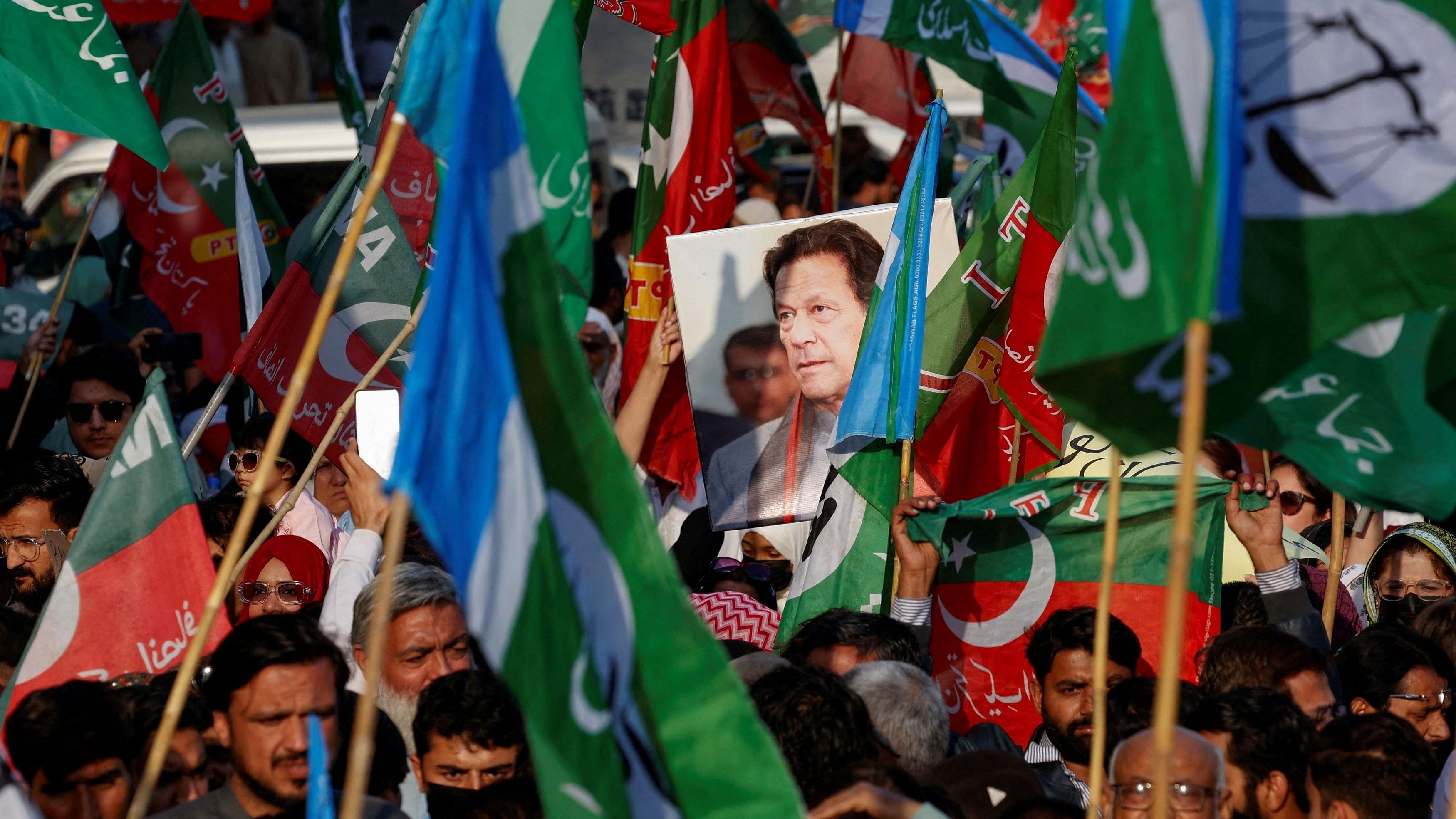 <div class="paragraphs"><p>A portrait of the former Prime Minister Imran Khan is seen amid flags of Pakistan Tehreek-e-Insaf (PTI).</p></div>