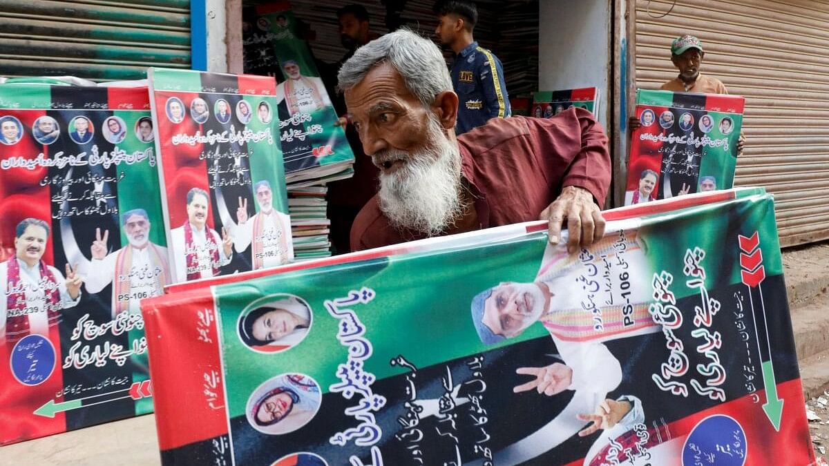 <div class="paragraphs"><p>A worker carries campaign posters of a political party to decorate the area, ahead of general elections, in Karachi, Pakistan</p></div>