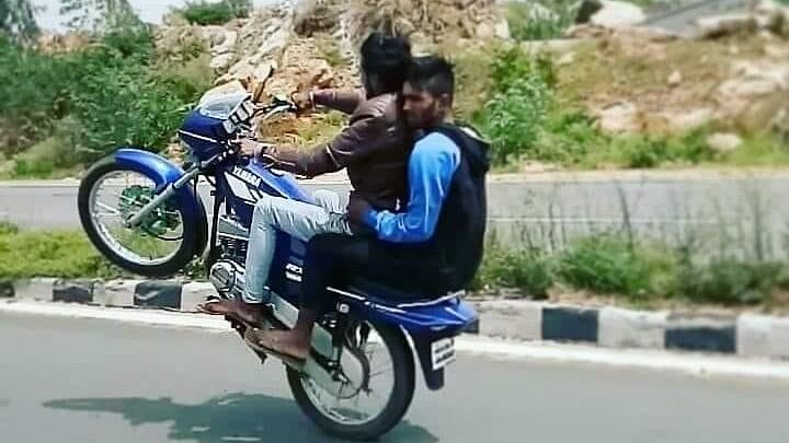 <div class="paragraphs"><p>Two guys on a bike doing wheelies.</p></div>