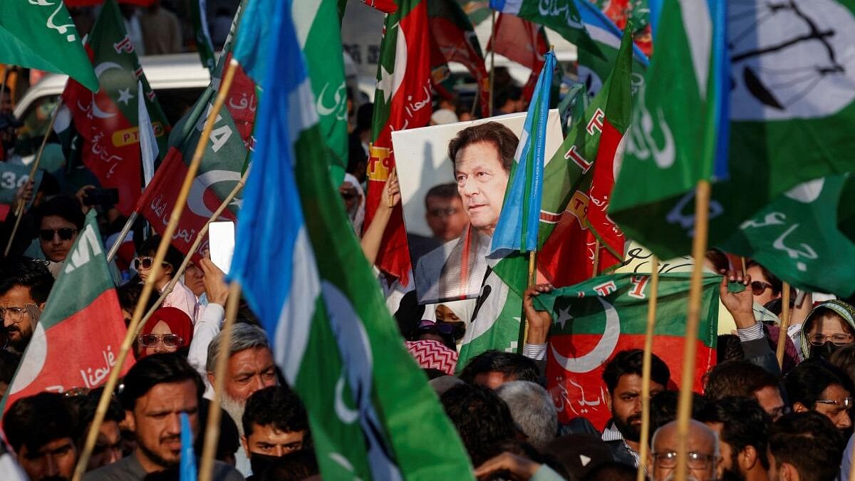 <div class="paragraphs"><p>A portrait of the former Prime Minister Imran Khan is seen amid flags of Pakistan Tehreek-e-Insaf (PTI) and the religious and political party Jamat-e-Islami (JI) as supporters attend a joint protest demanding free and fair results of the elections, outside the provincial election commission of Pakistan (ECP)in Karachi, Pakistan</p></div>