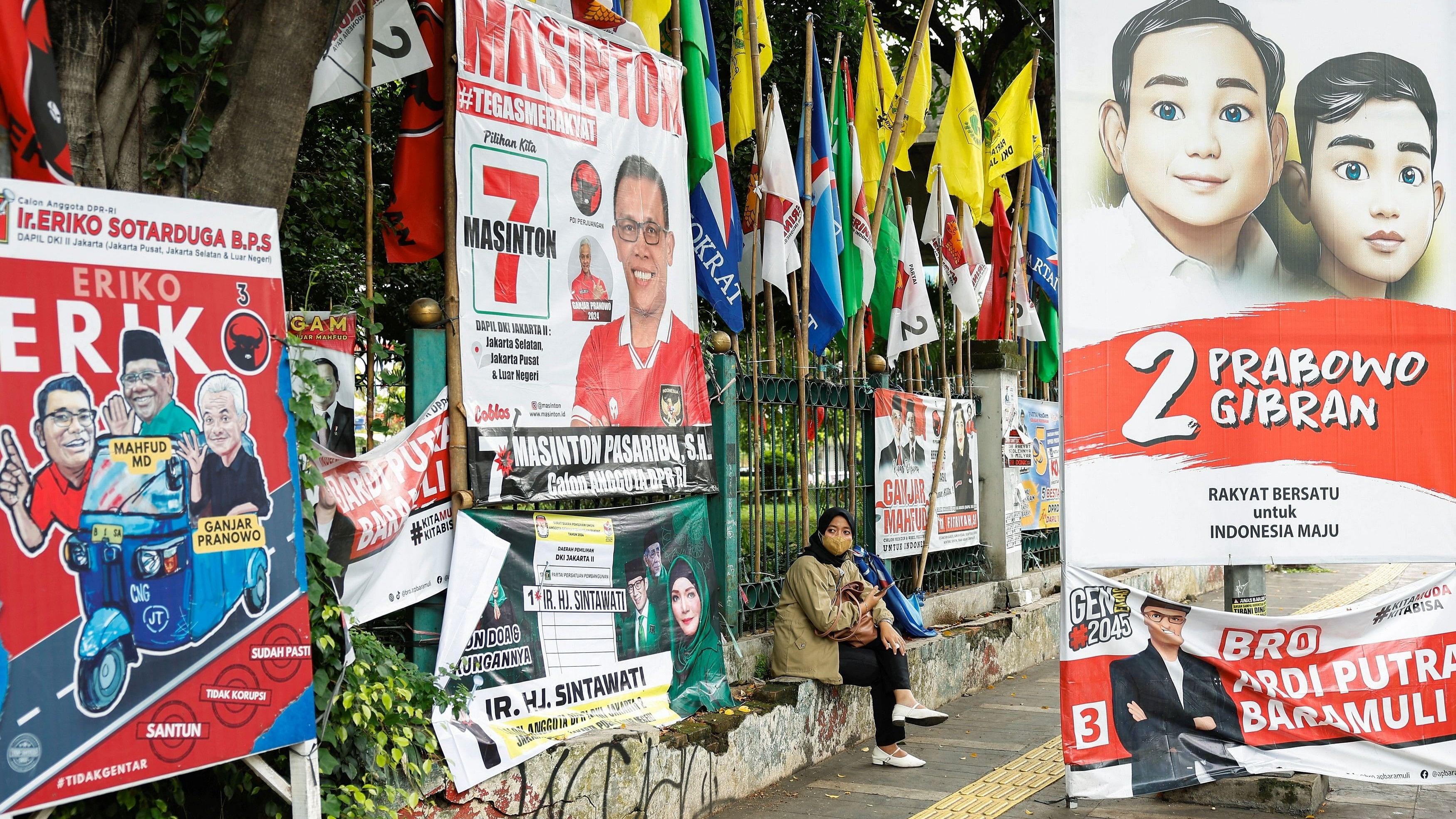 <div class="paragraphs"><p>A woman sits near flags and posters promoting the presidential and legislative candidates for the upcoming general election, in Jakarta, Indonesia.</p></div>