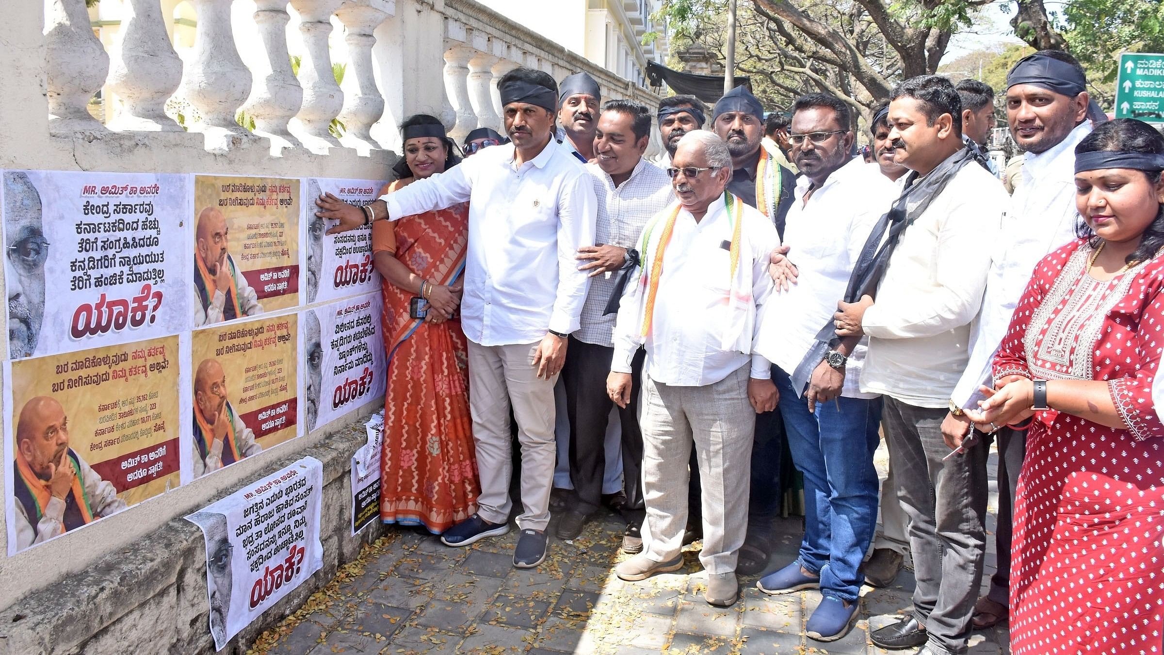 <div class="paragraphs"><p>Congress leaders and workers paste posters with slogans against Union Home Minister Amit Shah in Mysuru on Sunday. DH Photo</p></div>