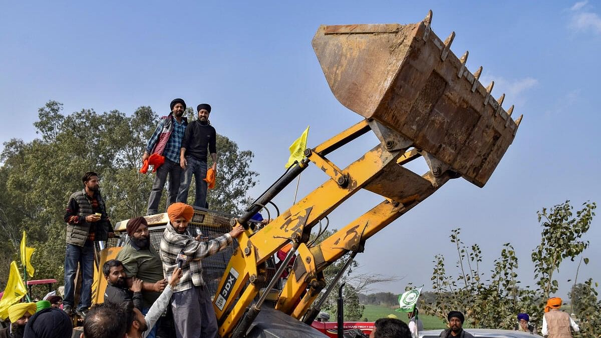 <div class="paragraphs"><p>Farmers near a backhoe loader modified to shield from police rubber bullets, during their protest</p></div>