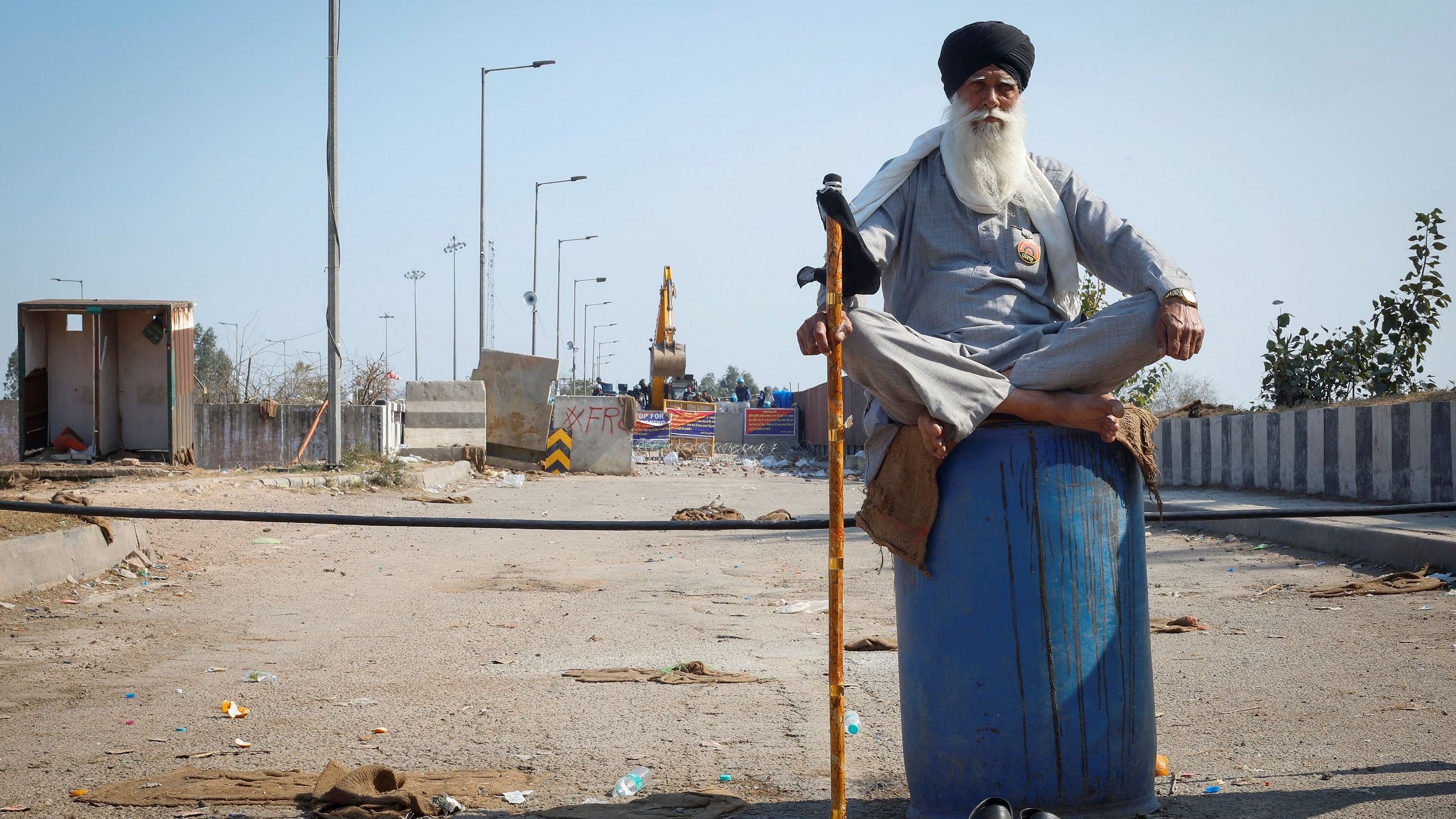 <div class="paragraphs"><p>A farmer sits on a plastic drum kept in front of police barricades, at a protest site during the march towards New Delhi to push for better crop prices promised to them in 2021, at Shambhu, the border between Punjab and Haryana, February 23, 2024. </p></div>