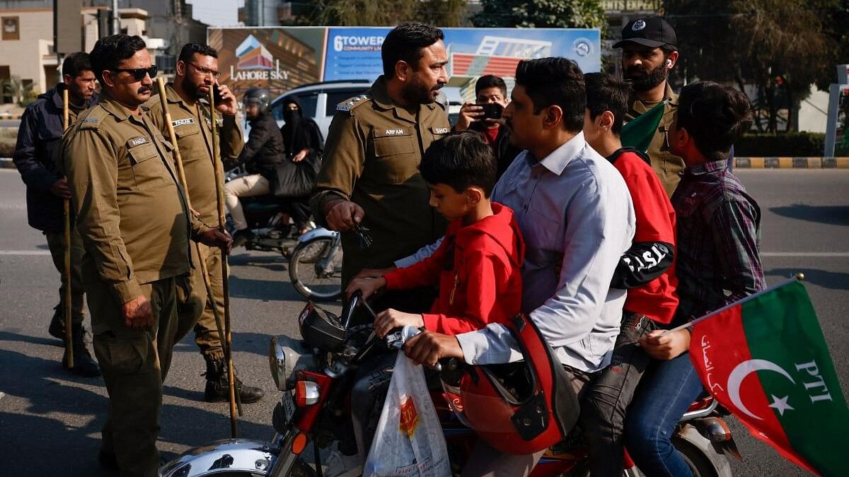 <div class="paragraphs"><p>Police officers stop a family riding on a motorcycle for displaying a Pakistan Tehreek-e-Insaf (PTI) flag, as supporters of PTI protest demanding free and fair results of the election in Lahore, Pakistan.</p></div>