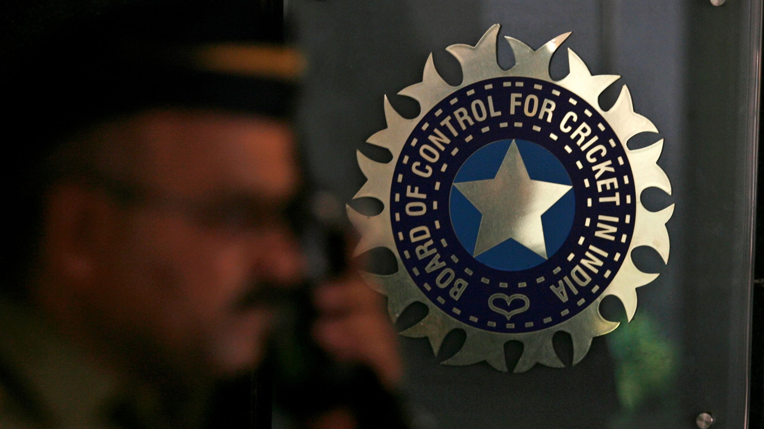 <div class="paragraphs"><p> A policeman walks past a logo of the BCCI.</p></div>