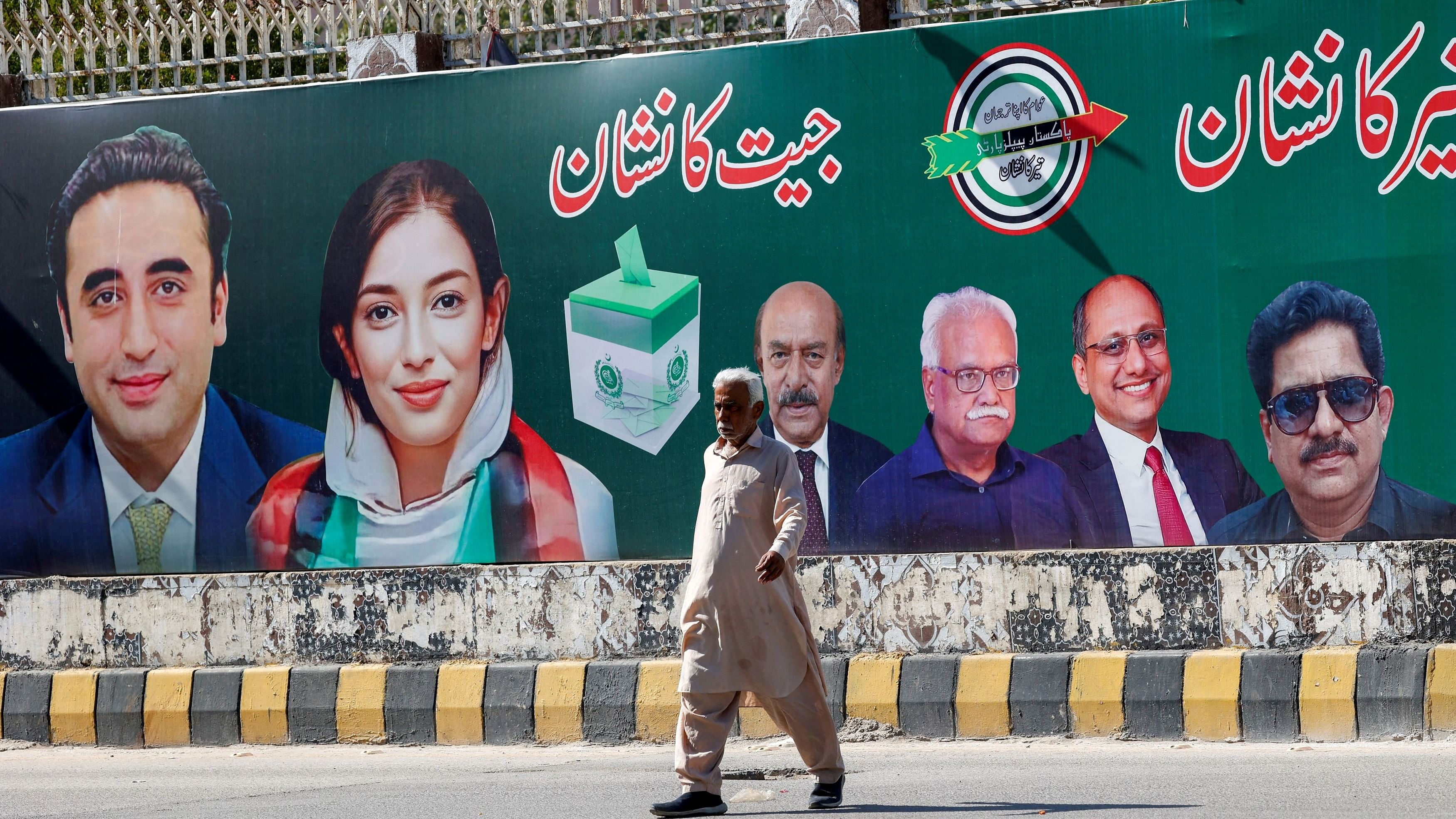 <div class="paragraphs"><p> A man walks next to a billboard displaying photos of politician Bilawal Bhutto and his sister Asifa Bhutto.</p></div>