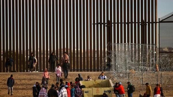 <div class="paragraphs"><p>Migrants seeking asylum in the United States gather near the border wall after crossing a razor wire fence deployed to inhibit their crossing into the US.</p></div>