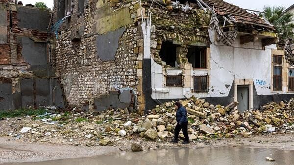 <div class="paragraphs"><p>A woman walks past houses destroyed by last year's earthquake, in Hatay, Turkey.</p></div>