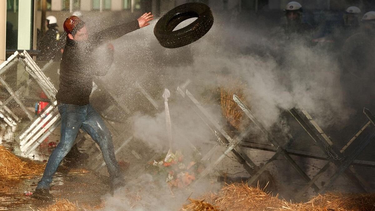 <div class="paragraphs"><p>A demonstrator throws a tyre over a barricade next to police officers in riot gear during a protest by farmers from Belgium and other European countries near the European Parliament  on the day of an EU summit in Brussels, Belgium.</p></div>