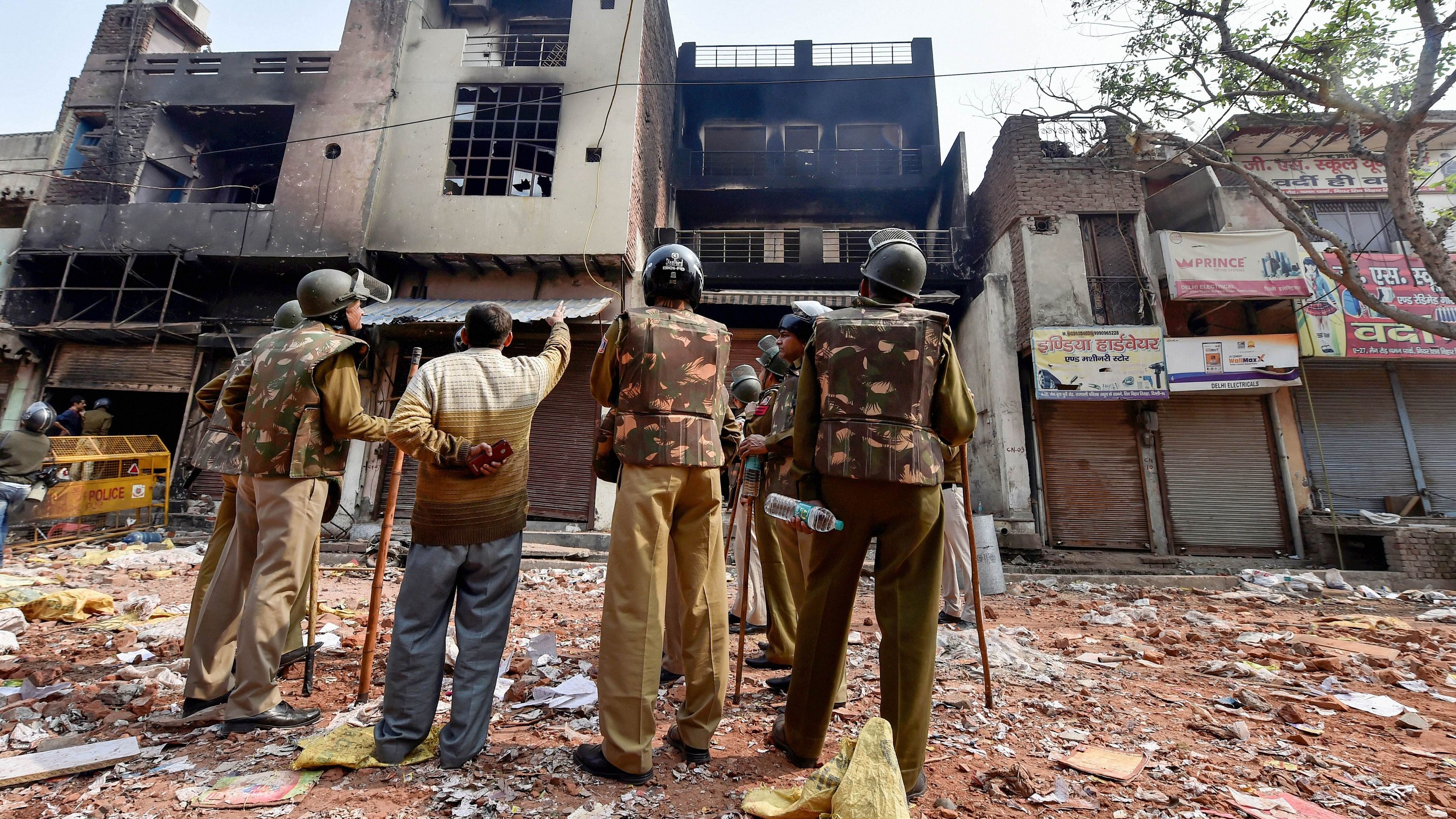 <div class="paragraphs"><p>Police personnel stand in front of a razed house in Delhi,&nbsp;Feb 26, 2020.</p></div>