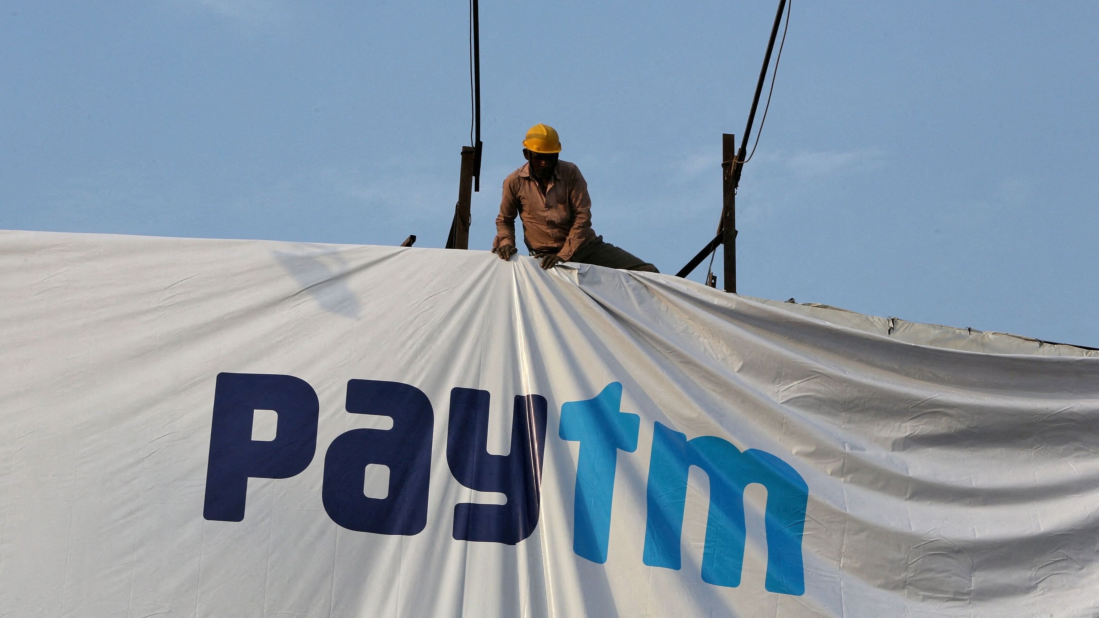 <div class="paragraphs"><p>A worker adjusts a hoarding of Paytm.</p></div>