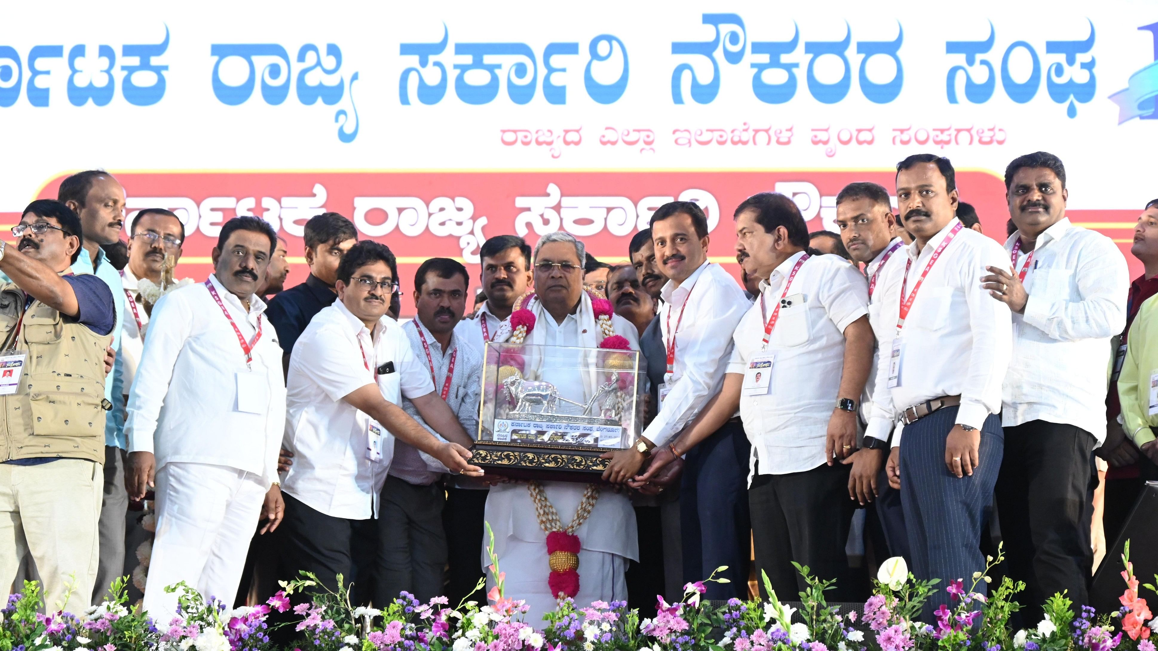 <div class="paragraphs"><p>State President C S Shadakshari felicitates Chief Minister Siddaramaiah during the 'State Government Employees Grand Conference', organised by Karnataka State Government Employees Association, at Palace Grounds in Bengaluru on Tuesday. </p></div>