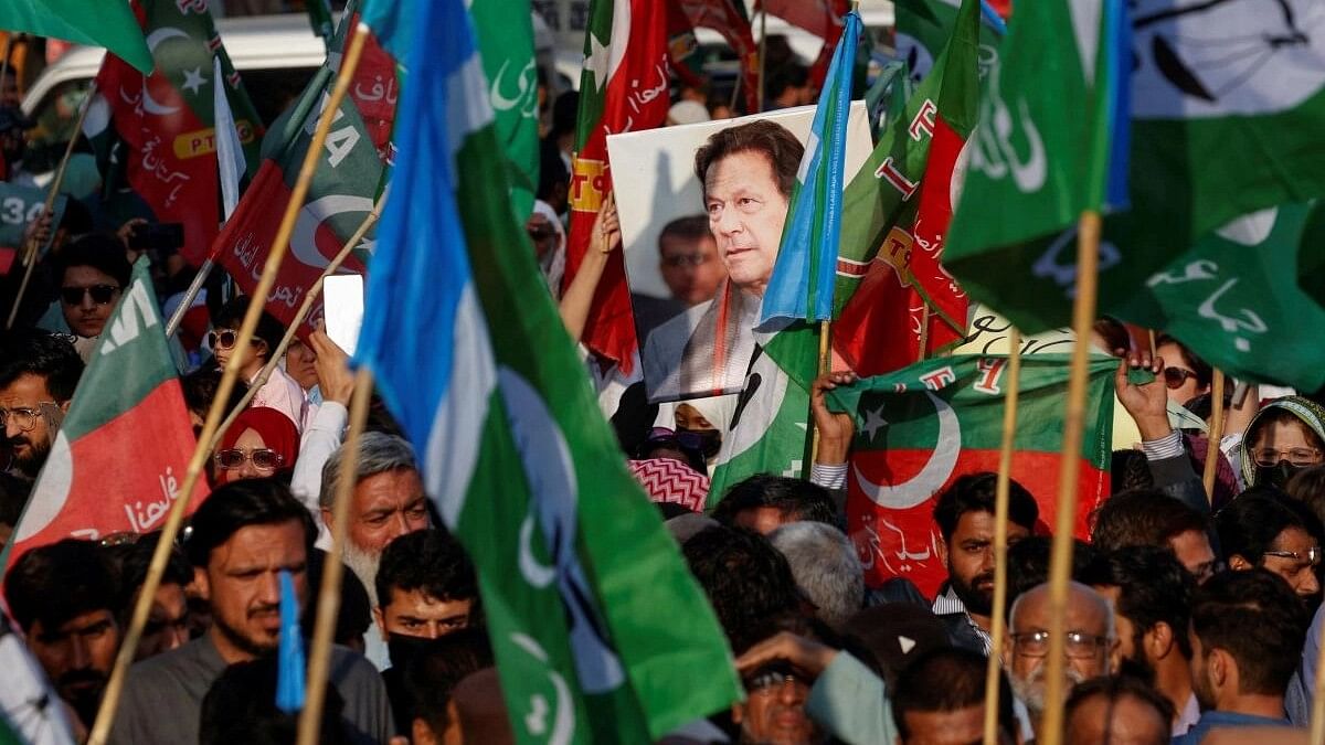 <div class="paragraphs"><p>A portrait of the former Prime Minister Imran Khan is seen amid flags of Pakistan Tehreek-e-Insaf (PTI) and the religious and political party Jamat-e-Islami (JI) as supporters attend a joint protest demanding free and fair results of the elections, outside the provincial election commission of Pakistan (ECP)in Karachi, Pakistan February 10, 2024.</p></div>