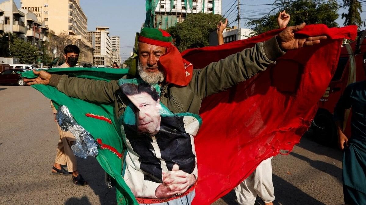 <div class="paragraphs"><p>A supporter of former Prime Minister Imran Khan's party, the Pakistan Tehreek-e-Insaf (PTI), with the party flag and a portrait of Imran Khan.</p></div>