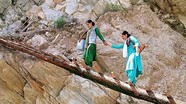 <div class="paragraphs"><p>Female health workers cross a temporary wooden bridge built on a road damaged by rains as they go for vaccination, in Najan village of Gadsa valley, in Kullu.</p></div>